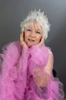 older woman with white hair dressed in a pink tulle goddess dress and a tiara