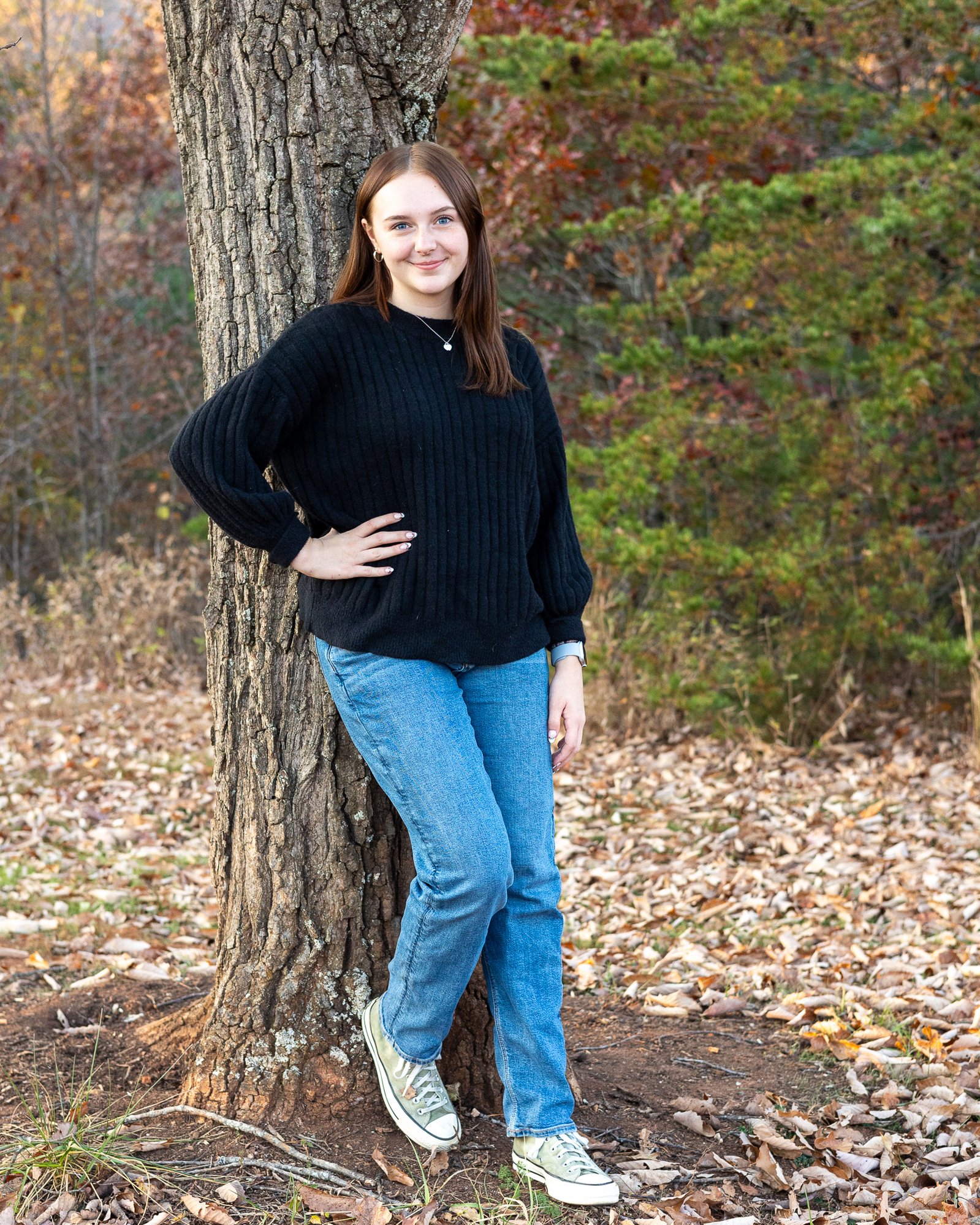 casual senior leaning on a tree in fall